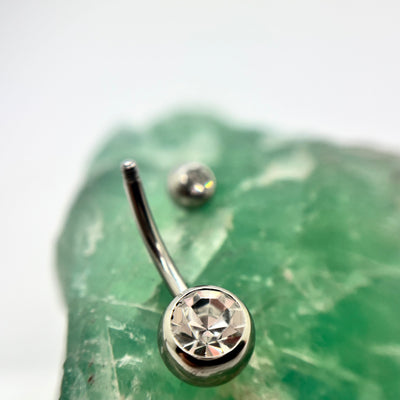 Stainless steel navel bar with a clear gemstone and a removed top bead