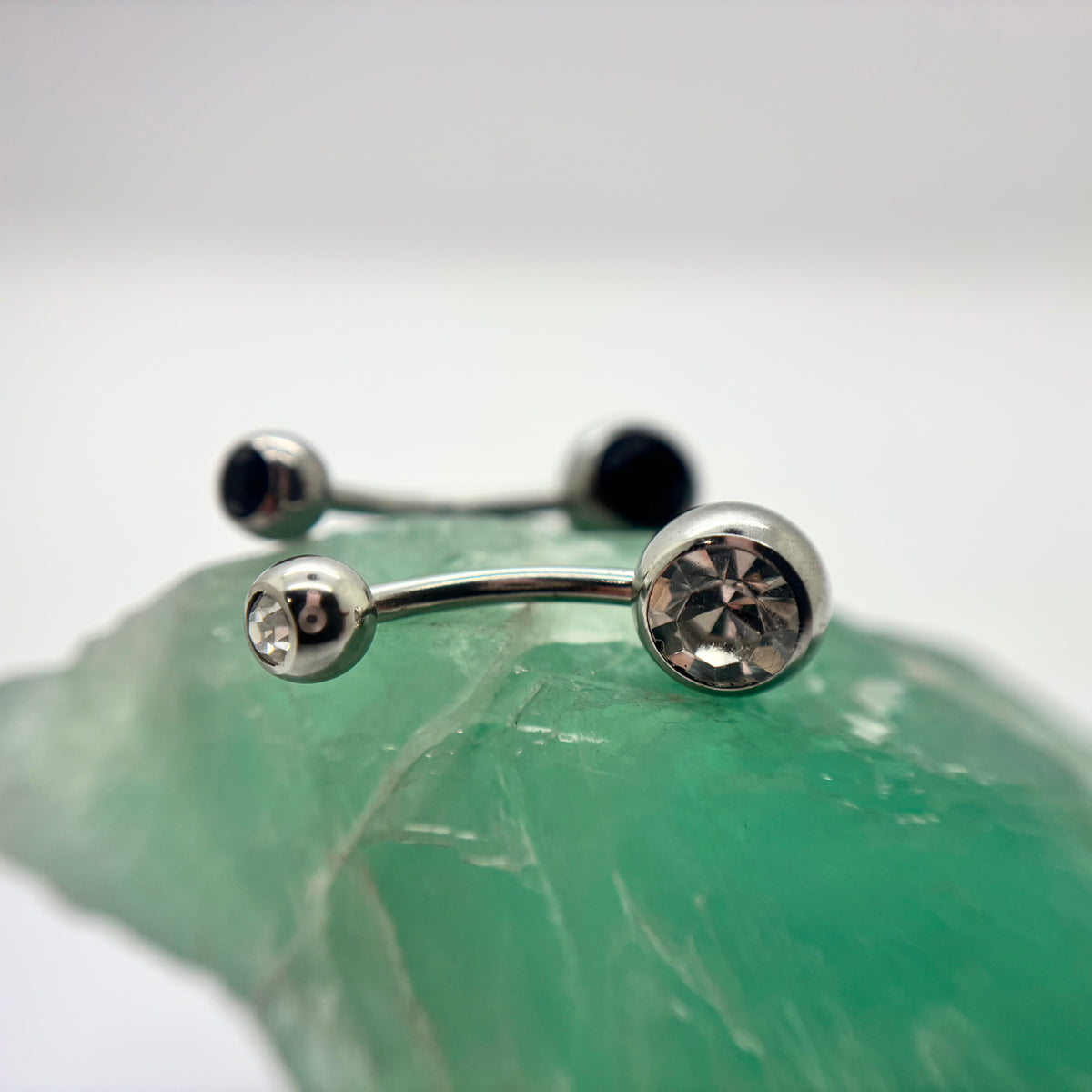 Stainless steel navel bars with clear and black gemstone ends