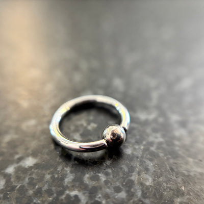 Polished stainless steel captive bead ring on dark stone