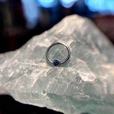 Titanium fixed-bead ring with a blue bead on pale stone