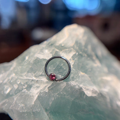Titanium fixed-bead ring with a pink bead on pale stone