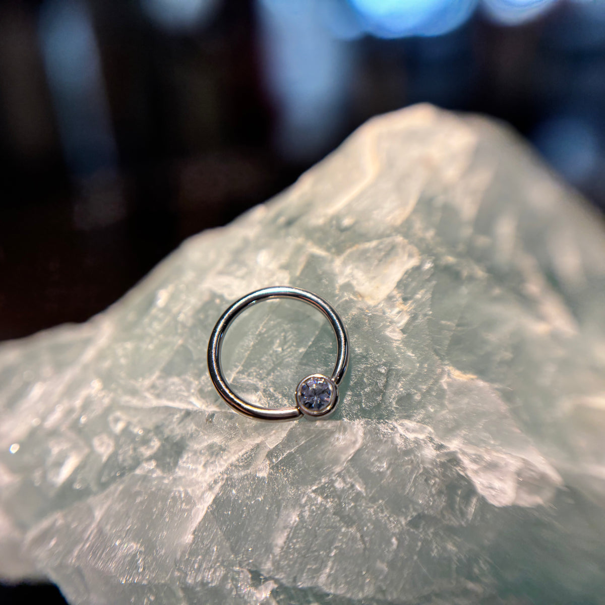 Titanium fixed-bead ring with a purple bead on pale stone