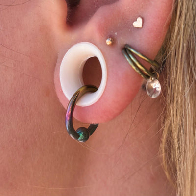 Titanium captive bead ring hanging through a white ear tunnel