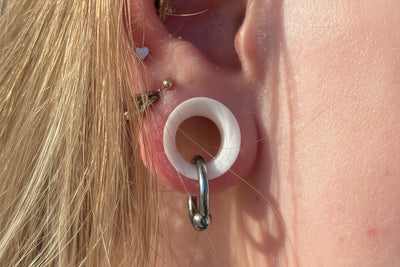 Polished titanium ring hanging through a white ear tunnel in a curated ear