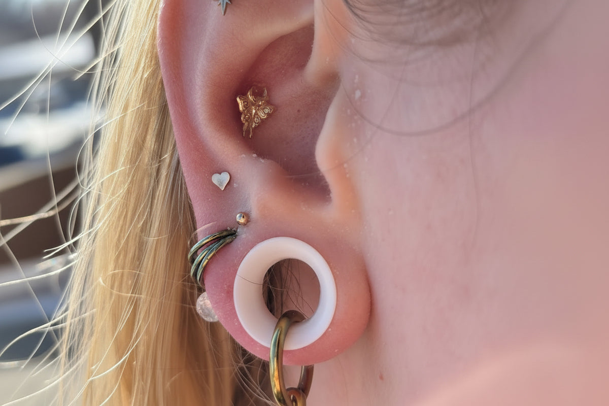 Polished titanium ring hanging through a white ear tunnel in a curated ear