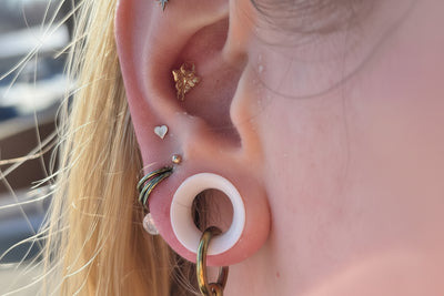 Polished titanium ring hanging through a white ear tunnel in a curated ear