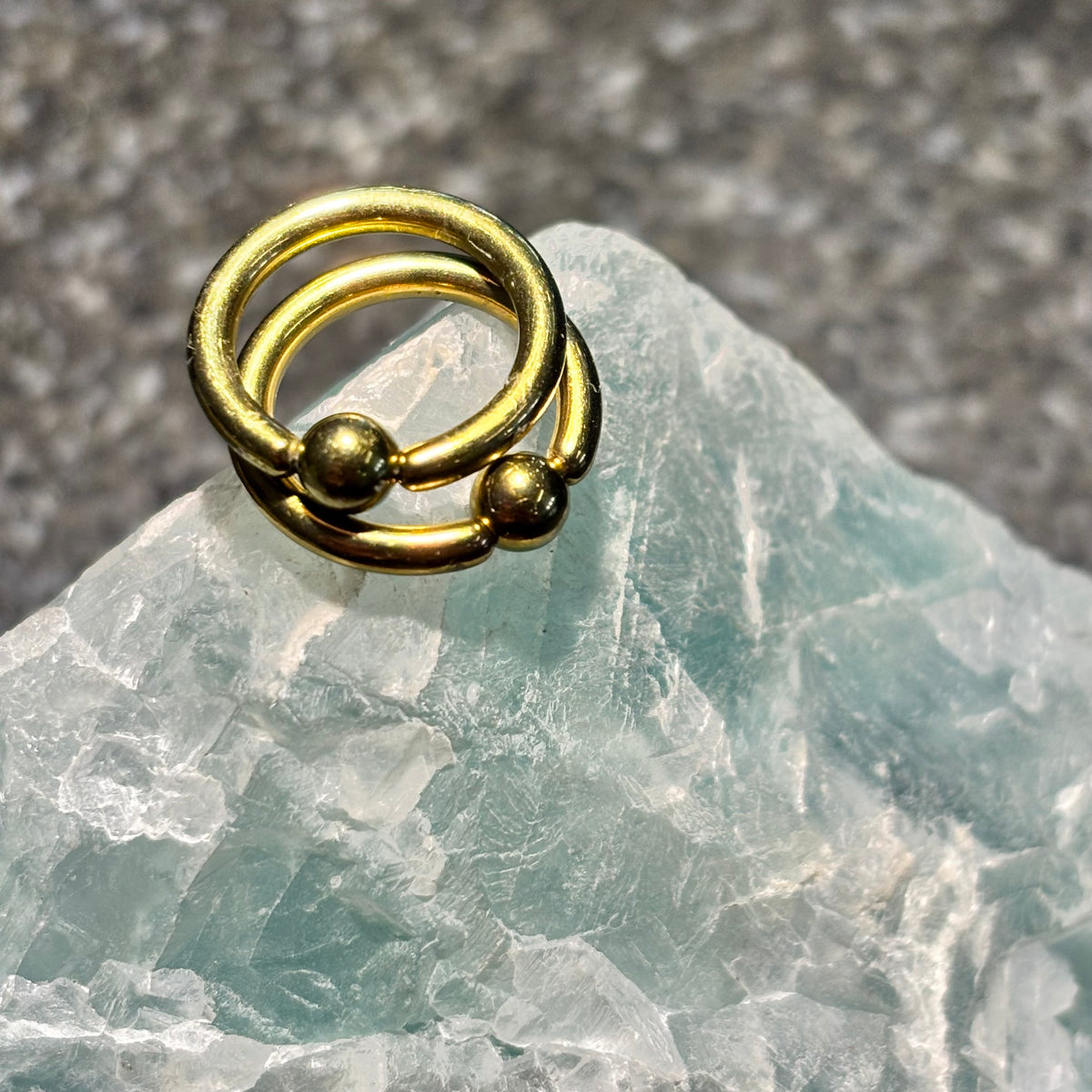 Two yellow anodized titanium captive bead rings on pale stone