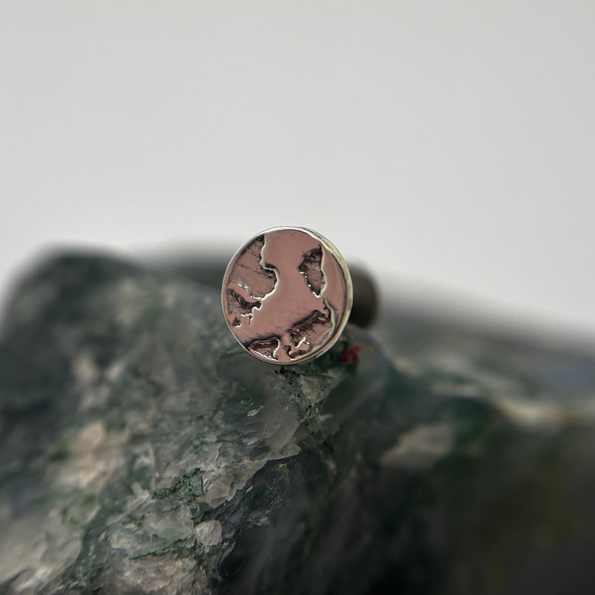 Silver Earth-shaped threadless end with engraved continents on a flat-back post