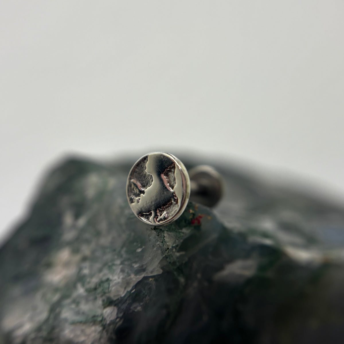 Silver Earth-shaped threadless end with engraved continents on a flat-back post