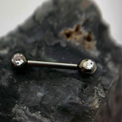 Straight barbell with clear gemstone ends on dark stone