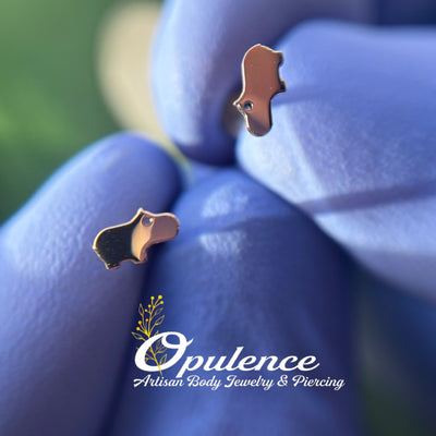 Gold baby hippo-shaped jewelry ends held in gloved fingers
