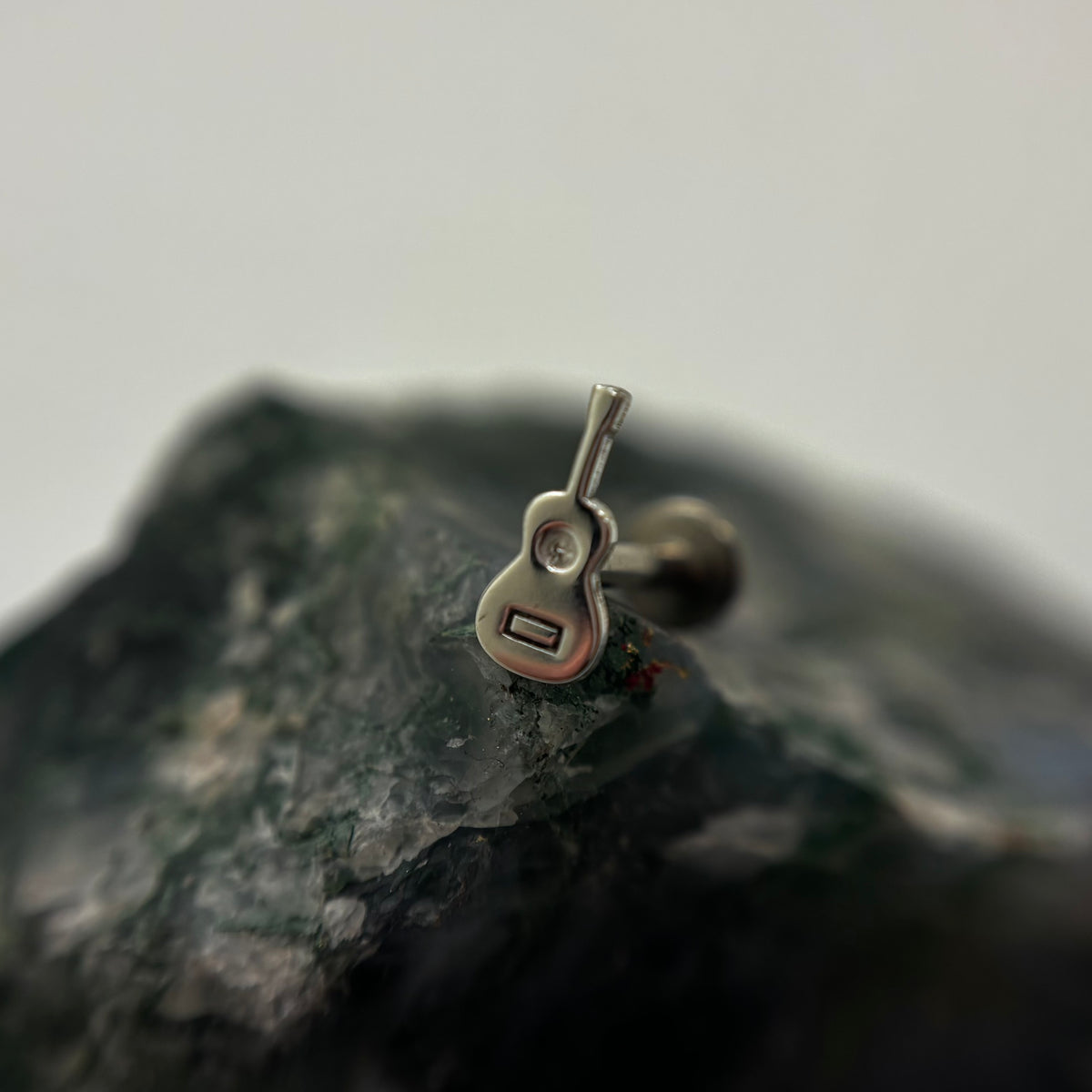 Silver guitar-shaped jewelry end on a flat-back post
