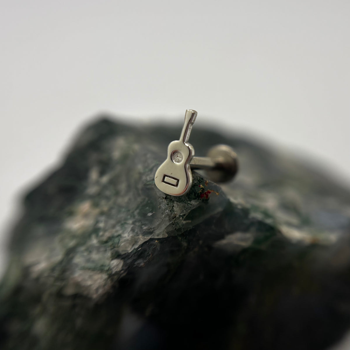 Silver guitar-shaped jewelry end on a flat-back post