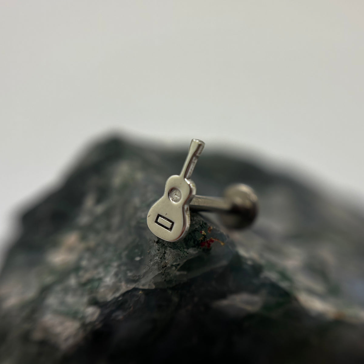 Silver guitar-shaped jewelry end on a flat-back post