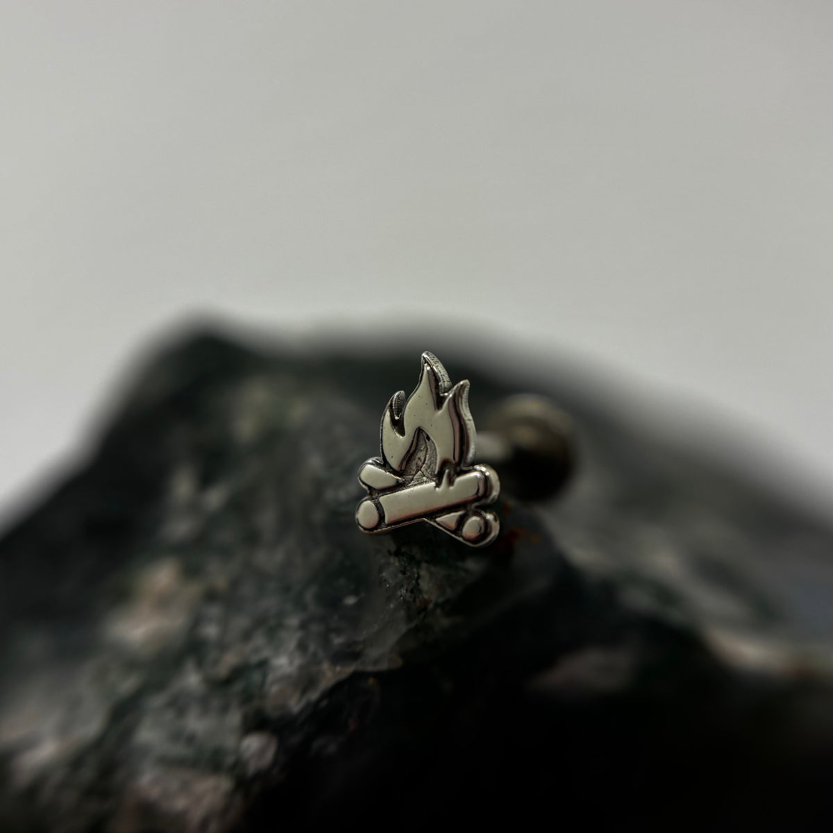 Silver campfire-shaped jewelry end with flame and log details