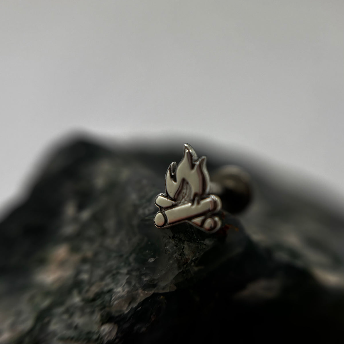 Silver campfire-shaped jewelry end with flame and log details