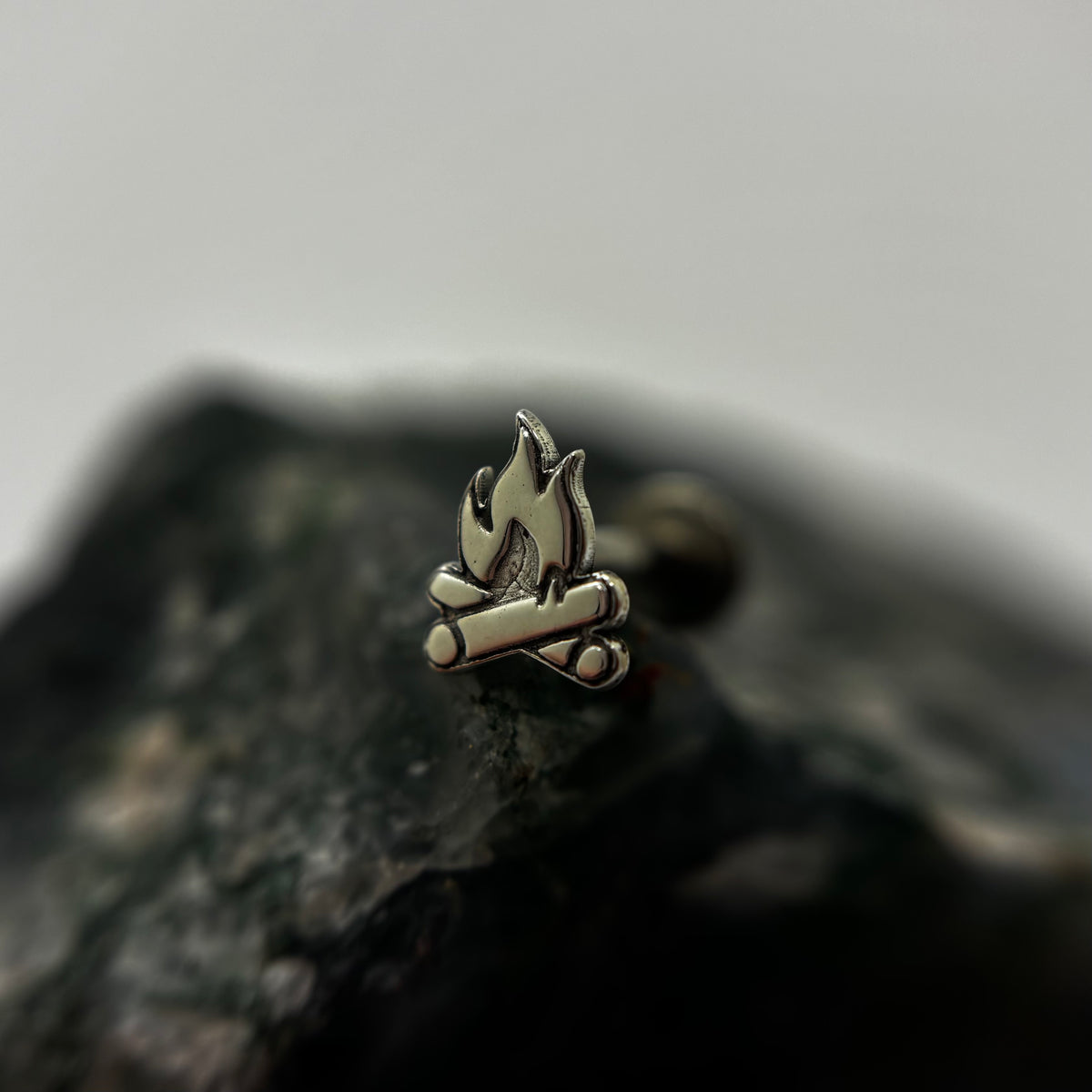 Silver campfire-shaped jewelry end with flame and log details