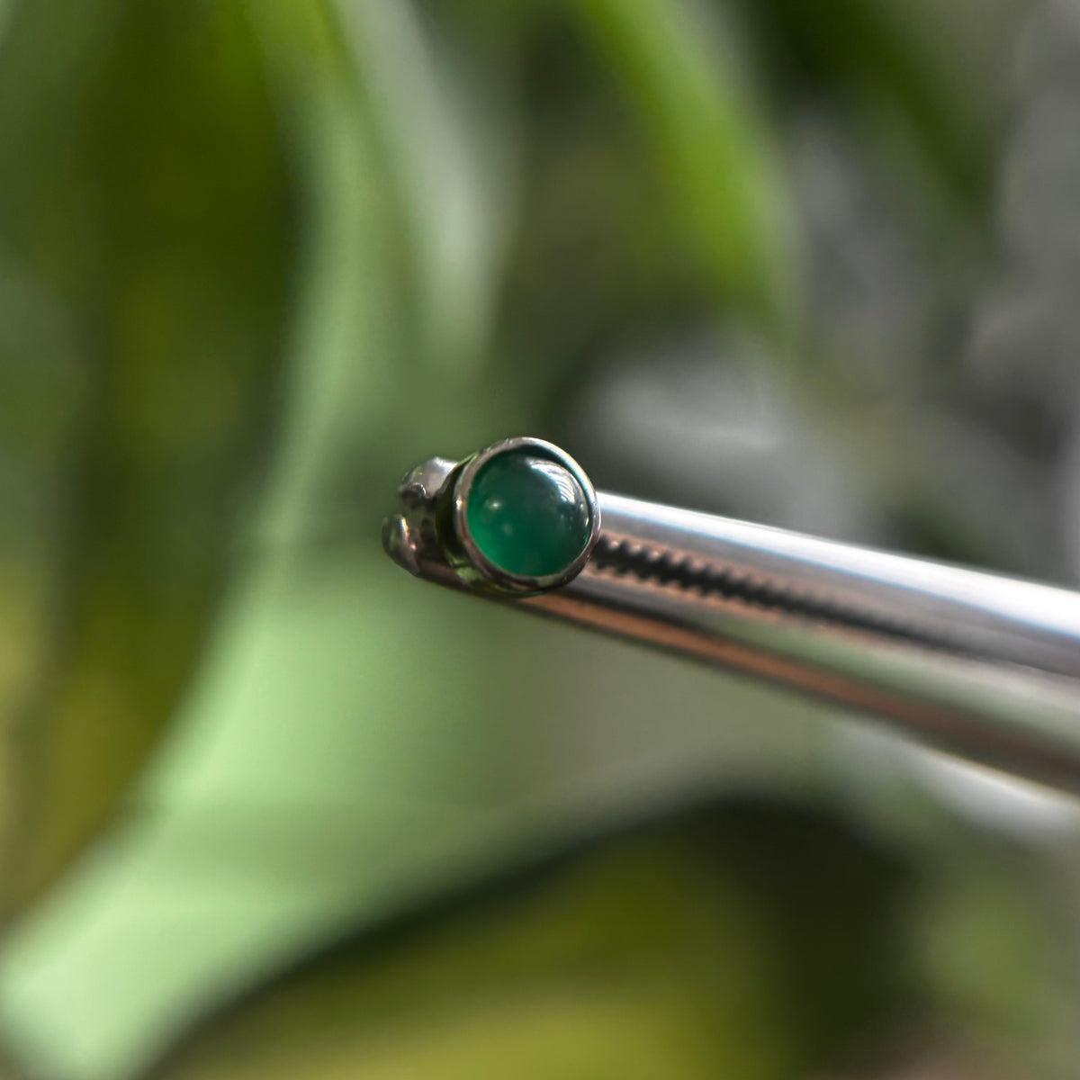 Green agate jewelry end held with tweezers