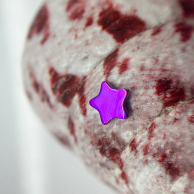 Purple titanium star-shaped jewelry end on patterned fabric