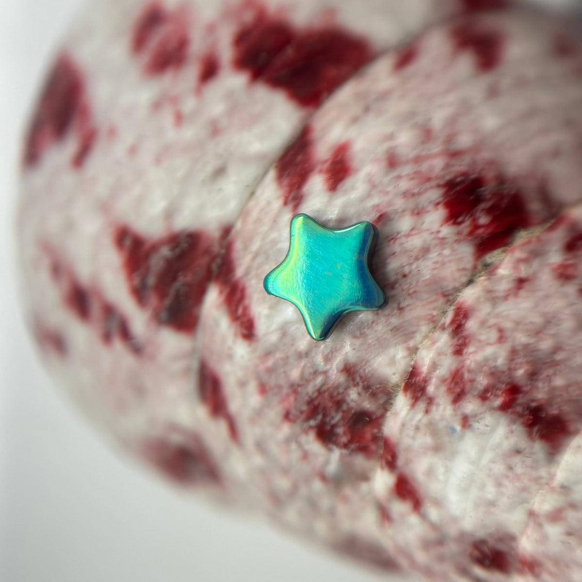 Green and blue titanium star-shaped jewelry end on patterned fabric