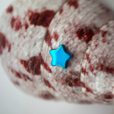 Blue titanium star-shaped jewelry end on patterned fabric