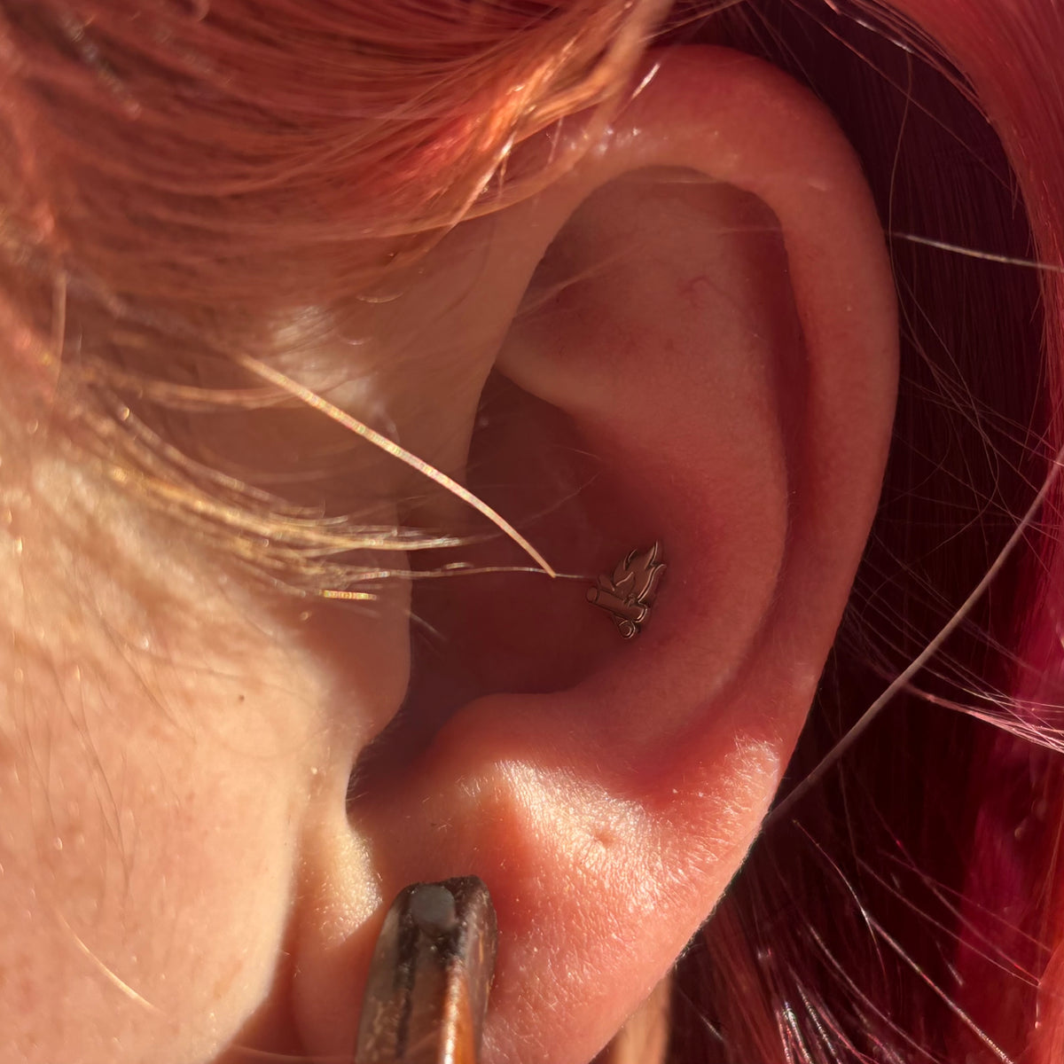 Silver campfire jewelry worn in an upper-ear piercing