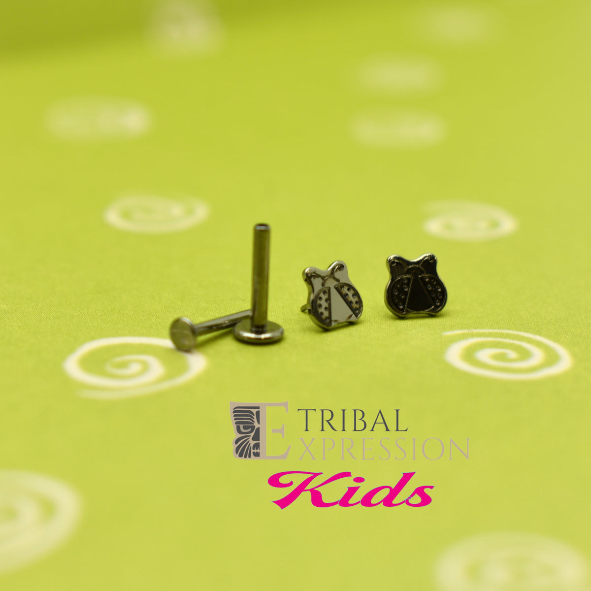 Ladybug-shaped titanium jewelry ends beside a flat-back post