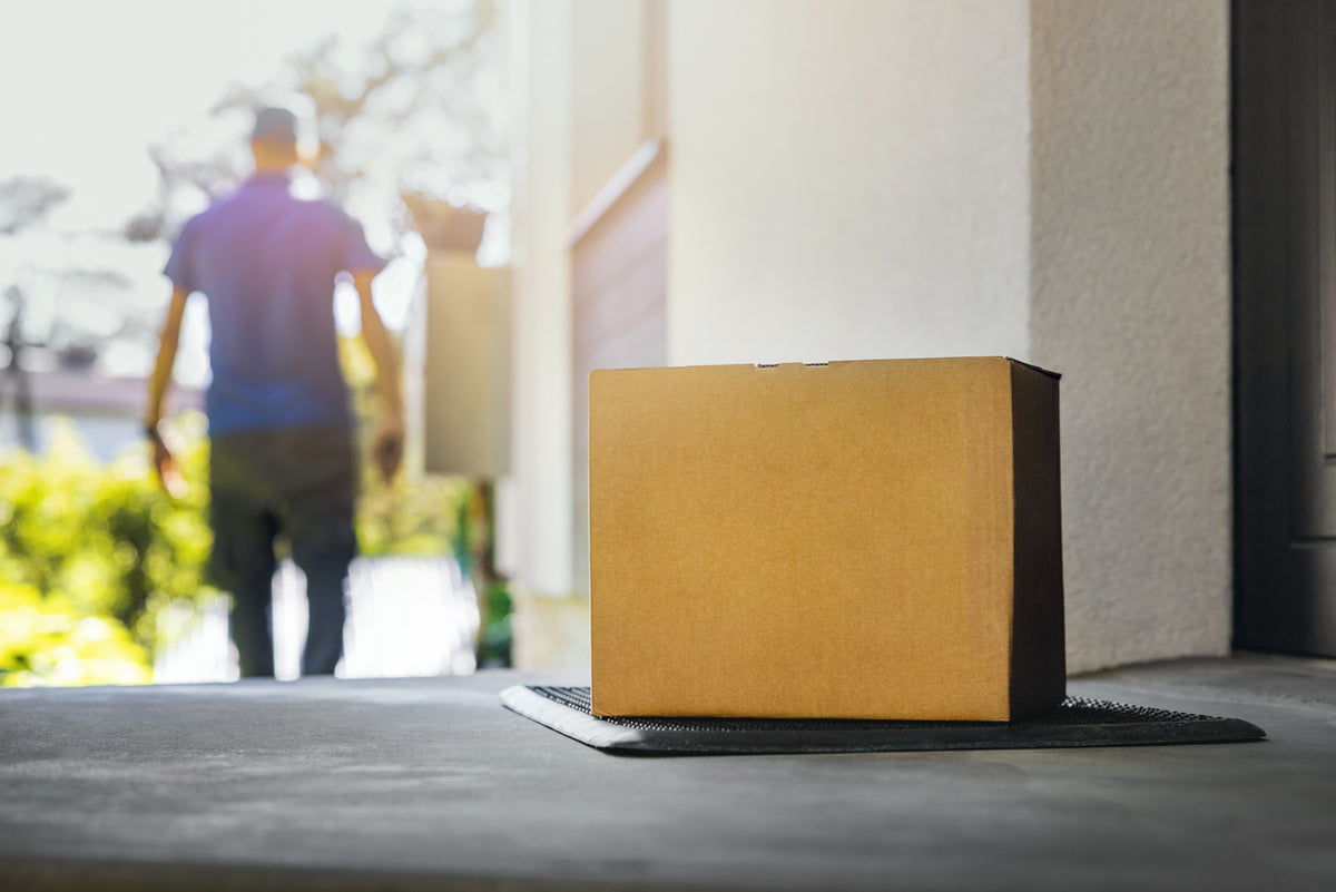 Delivery parcel at a front door with a courier in the background
