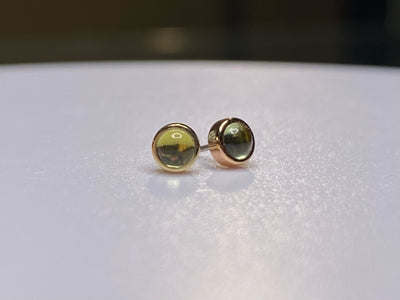 Pair of green peridot studs in yellow and rose gold settings