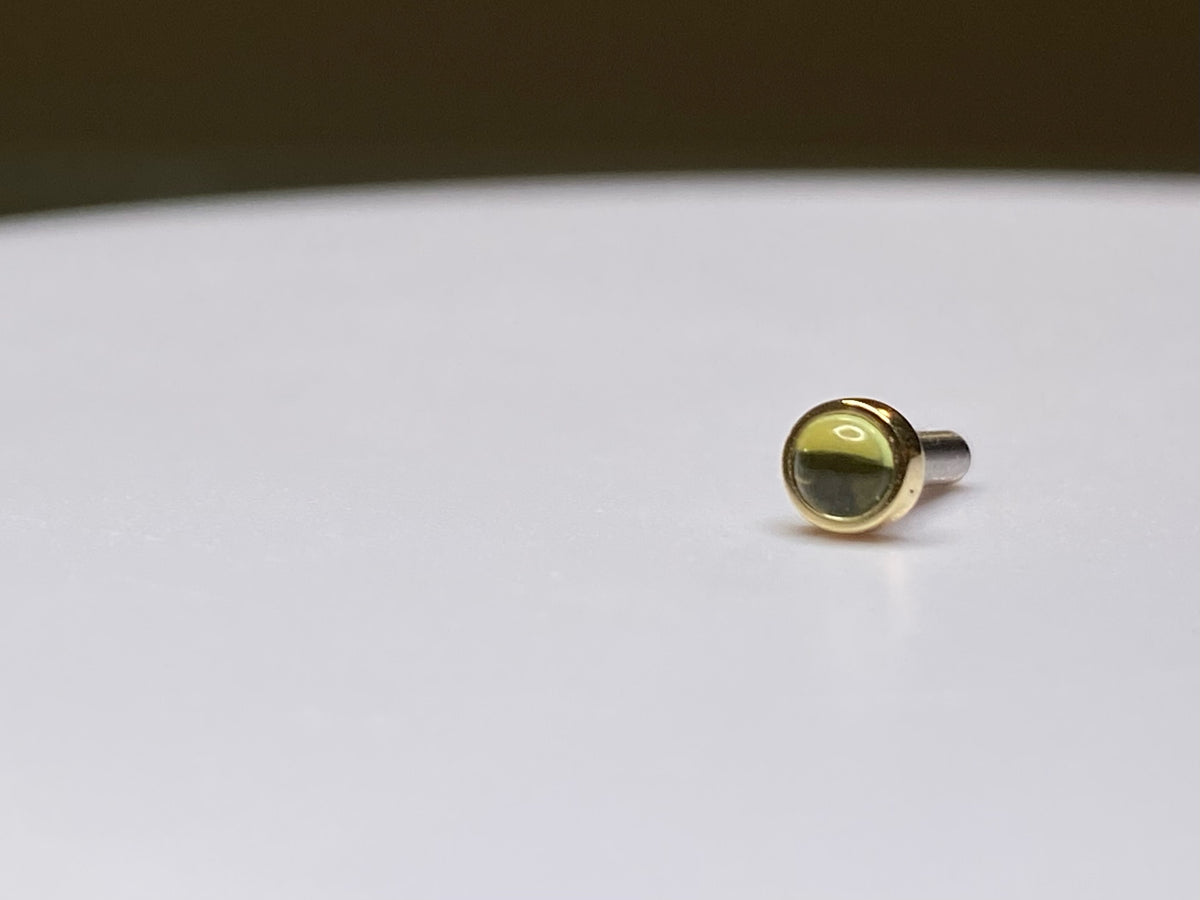 Gold bezel-set peridot stud with its post visible