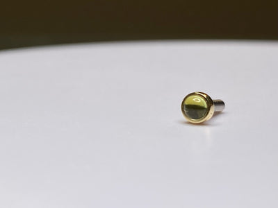 Gold bezel-set peridot stud with its post visible