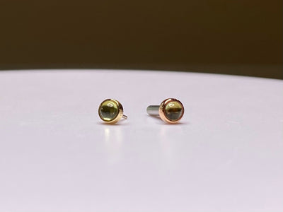 Pair of green peridot studs in yellow and rose gold settings