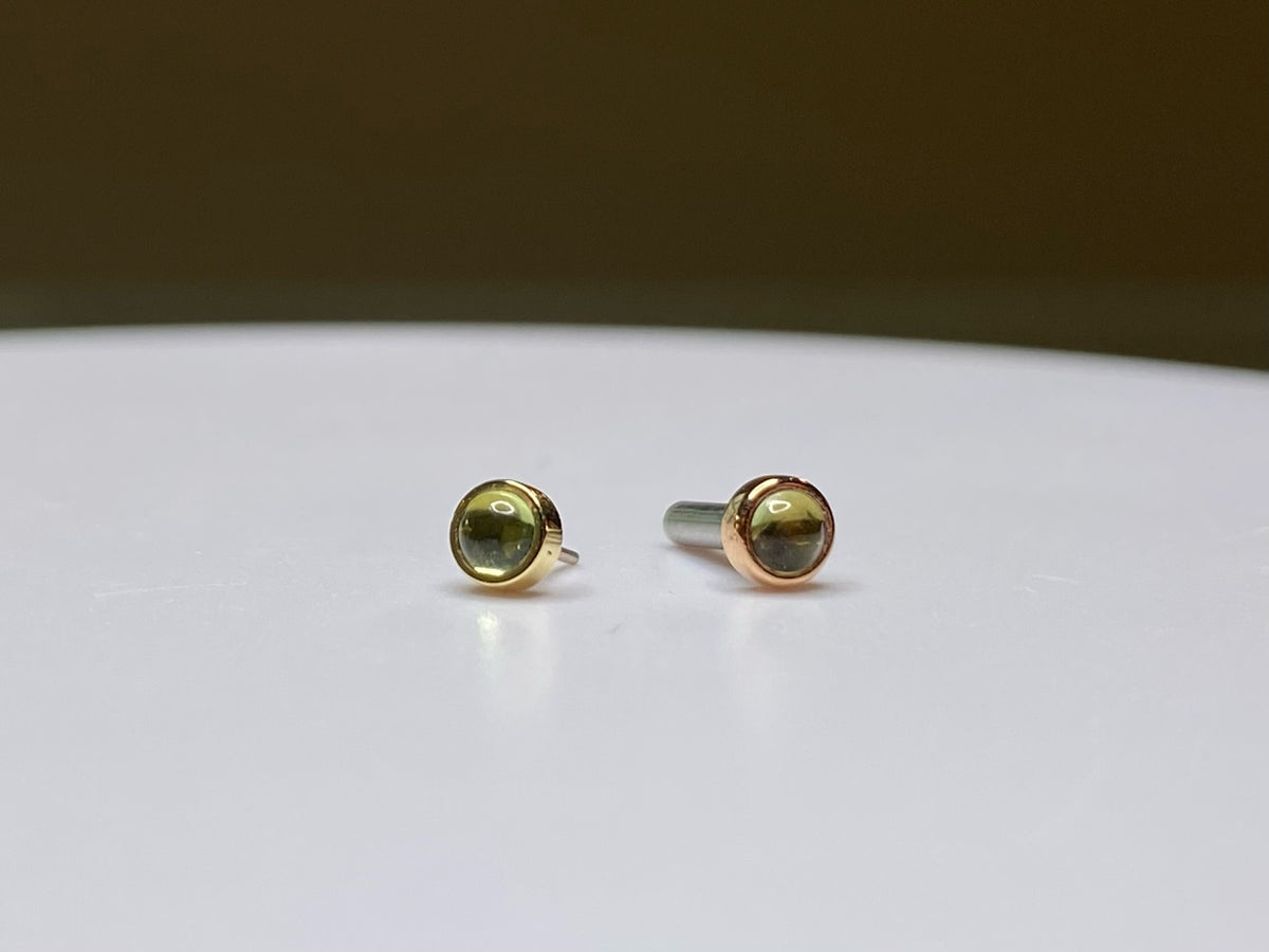 Pair of green peridot studs in yellow and rose gold settings
