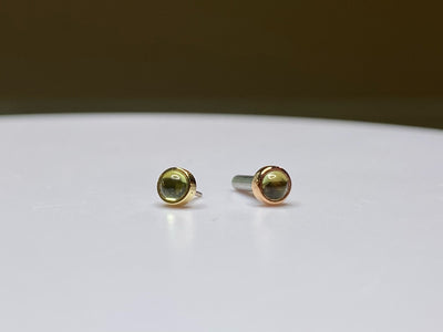 Pair of green peridot studs in yellow and rose gold settings