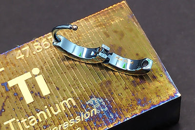 Blue titanium clicker shown open on a titanium display block