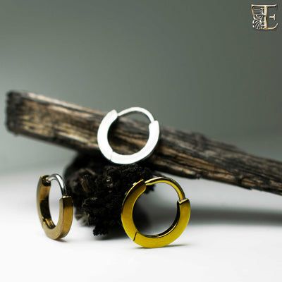 Silver and gold-toned titanium clicker rings on a branch