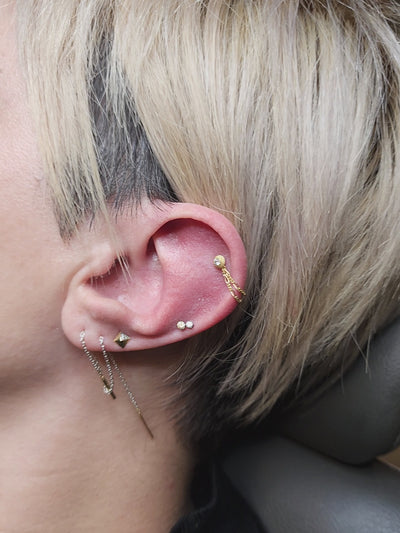 Ear curation with small gemstone studs, hoops and a hanging chain