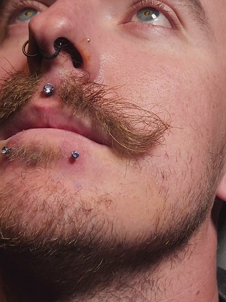 Violet-coloured lip jewelry shown in a close-up piercing film