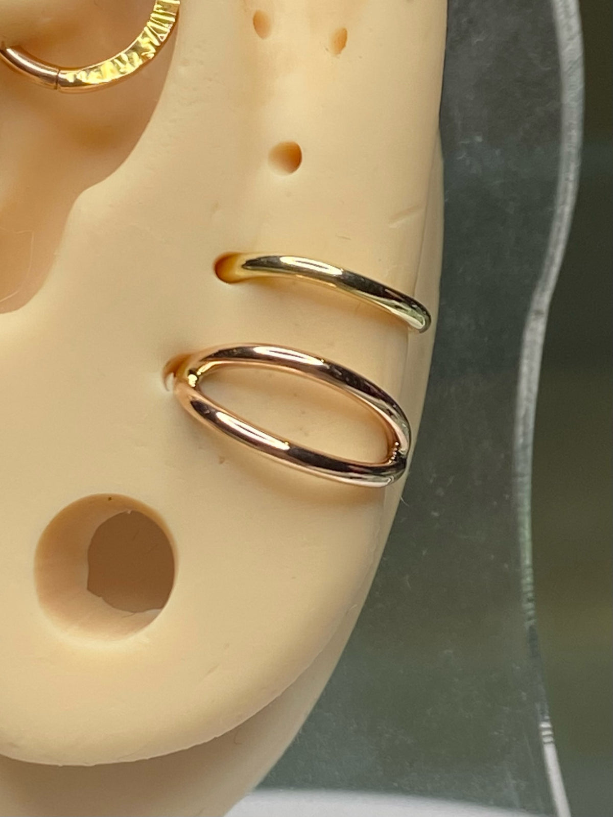 Gold split seam rings on an ear display model