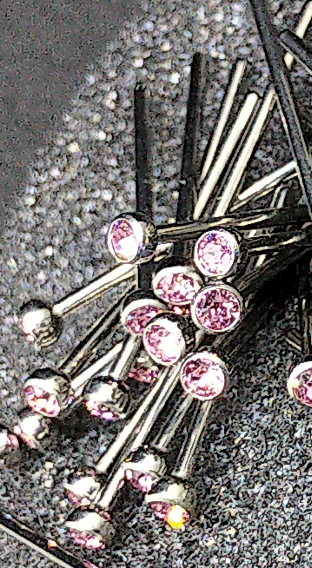 Pink cubic zirconia titanium nostril studs on a textured display