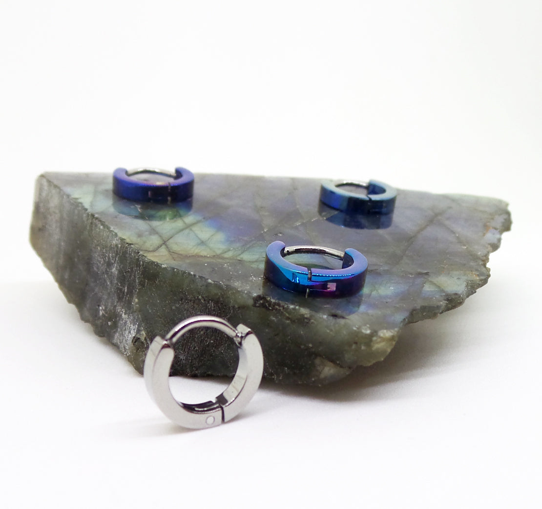 Blue and polished titanium clicker rings displayed on stone