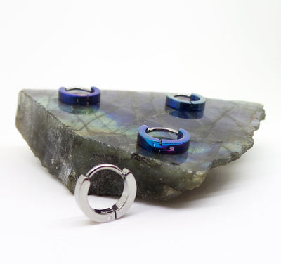 Blue and polished titanium clicker rings displayed on stone