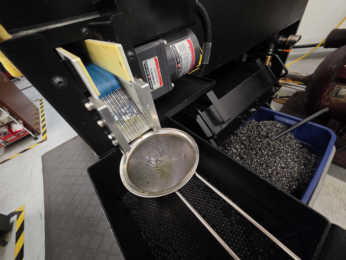 Freshly machined metal components collected beside a CNC machine in the Tribal Expression workshop